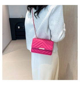 Detailed side view of quilted rose red crossbody bag with golden chain and V-pattern