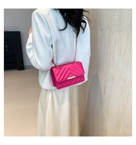 Detail of magenta quilted bag with V-shaped chevron stitching and golden chain strap