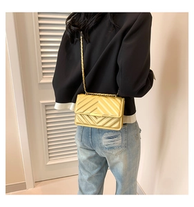 Close-up of golden chain strap and V-quilted faux leather finish on small square bag
