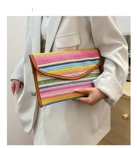 Close-up of colorful striped straw clutch with envelope flap and brown leather trim