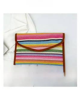 Detailed close-up of colorful striped woven envelope clutch with brown faux leather trim