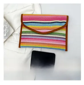 Detail view of woven envelope clutch with colorful stripes and phone for size reference