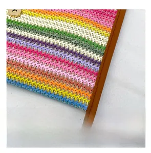 Detail of colorful striped woven clutch with brown leather trim and metal clasp