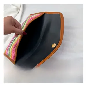 Detail of colorful woven envelope clutch with magnetic closure and smooth lining