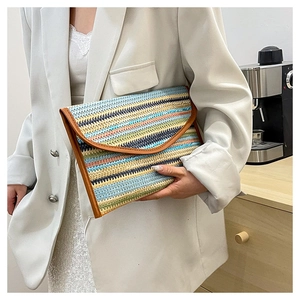 Close-up of a colorful woven striped clutch bag with brown leather trim held by a model