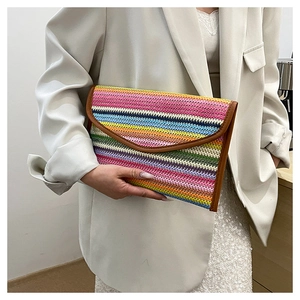 Detailed view of hand-held colorful woven envelope clutch with brown leather trim