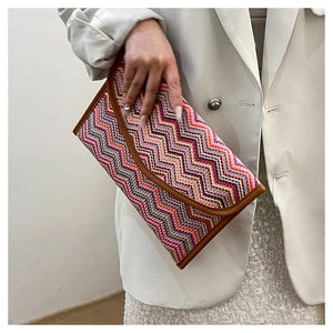 Close-up of Bohemian woven clutch with colorful geometric wave patterns and brown trim