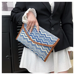 Detail of blue and white zigzag woven envelope clutch with brown leather trim