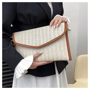 Detail of woven straw envelope clutch with brown leather trim and magnetic flap