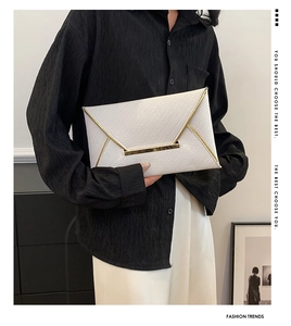 Détail de la pochette enveloppe blanche avec texture tissée et fermoir en métal doré