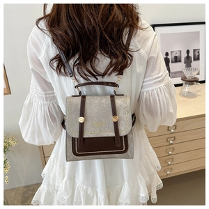 Model showing retro brown faux leather dual-use backpack with gold buckle in home setting