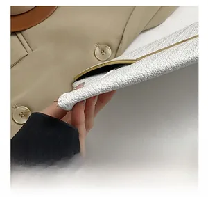 Gros plan détaillé sur la texture en tweed blanc et bordure dorée du sac de soirée chic