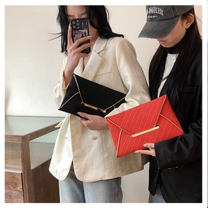 Chic envelope clutch bag with V-shaped metal trim in red and black woven texture