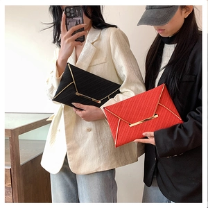 Detail of minimalist envelope clutches in black and red with woven texture and gold metal trim