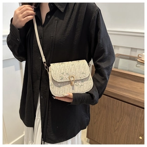 Detail of oatmeal woven saddle bag with delicate floral embroidery and gold heart clasp