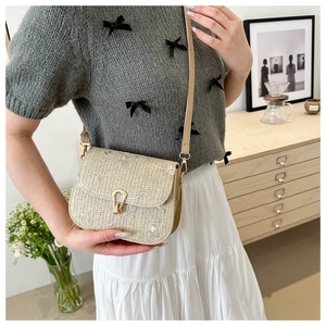 Detail view of woven straw crossbody bag with floral embroidery and gold metal lock