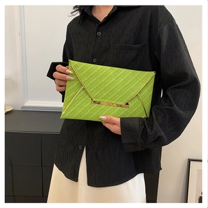 Detail of green envelope clutch with diagonal texture and gold metal trim