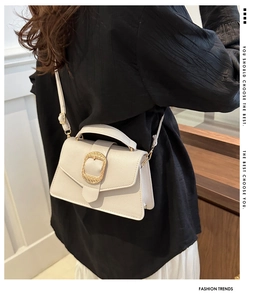 Detailed view of cream leather crossbody bag featuring a large gold woven metal buckle