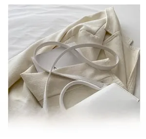 Detailed view of white faux leather crossbody bag with light gold decorative metal chain