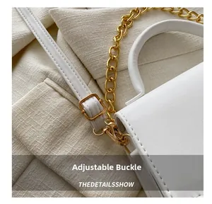 Close-up of golden adjustable buckle and chain strap on a white fashion handbag