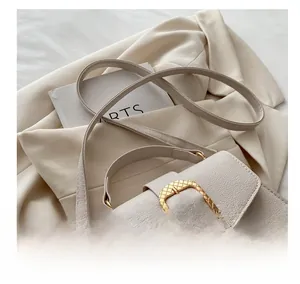 Detail of cream crossbody bag featuring a golden square buckle and adjustable shoulder strap