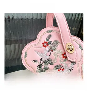 Détail du sac bandoulière rose avec broderie de grue traditionnelle et chaîne dorée