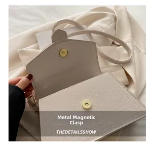Detailed close-up of a golden metal magnetic closure on a cream lychee leather handbag
