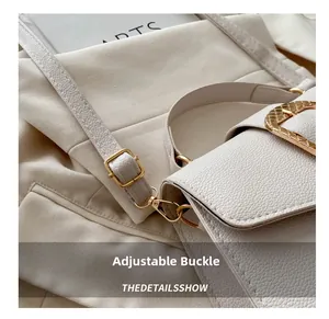 Close-up of golden adjustable buckle on white lychee grain leather handbag strap