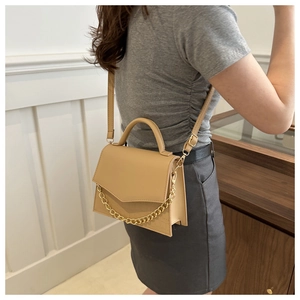 Detail of milk tea leather crossbody bag with chunky gold chain and slim shoulder strap