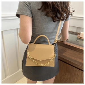 Detail of khaki crossbody bag featuring bold gold chain decor and smooth PU leather