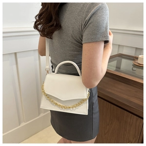 Model showcasing a white crossbody bag with crocodile texture and gold chain detail