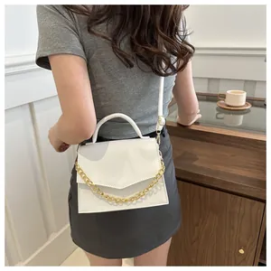 Chic white crossbody bag with crocodile texture and gold chain on a female model
