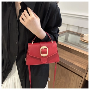 Detail of red lychee pattern leather handbag featuring a gold square metallic buckle