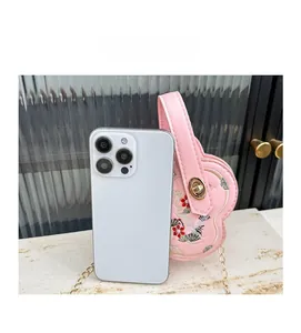 Sac à bandoulière rose en forme de fleur avec broderie et chaîne à côté d'un téléphone