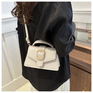 Detailed view of cream leather mini bag with textured golden rectangular buckle