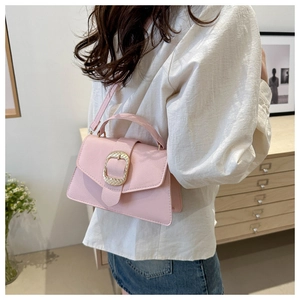 Detail of light pink pebble leather handbag with gold woven buckle and handle