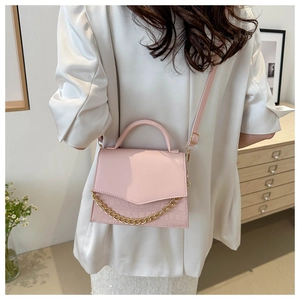 Pink crossbody bag featuring crocodile texture and elegant gold chain detail in lifestyle setting