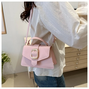 Detail of pink crossbody bag with a large gold oval buckle and fine leather texture