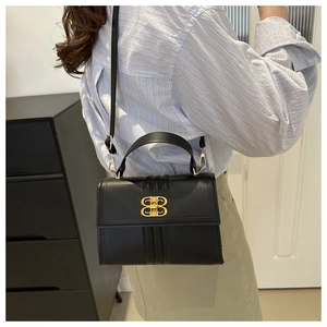 Détail d'un sac bandoulière en cuir noir avec une boucle dorée distinctive à double anneau
