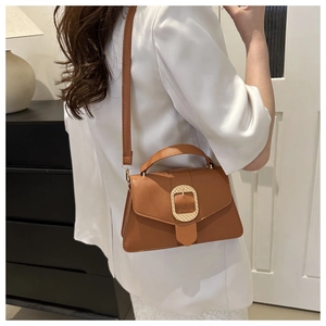 Brown leather handbag styled with a white blazer, showing the golden square buckle detail