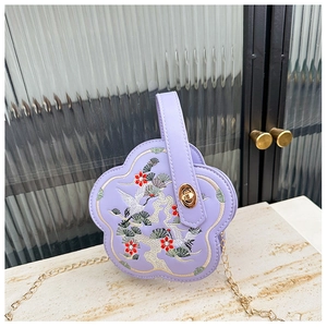 Détail du sac fleur de prunier lavande avec broderie de grue et bandoulière chaîne dorée
