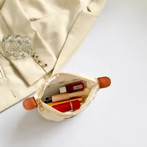 Vista dall'alto della trousse trapuntata crema con ampia capacità per rossetti e trucchi