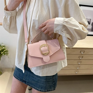 Pink lychee texture crossbody bag with gold buckle and top handle in a cozy home setting