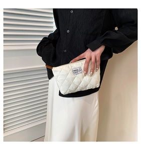 Dettaglio della pochette beige a rombi con toppa FASHION e trama trapuntata