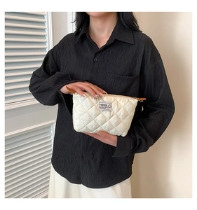 Détail du sac à main matelassé blanc avec motif en losange et étiquette Fashion tenu