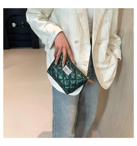 Dettaglio della pochette trapuntata verde scuro con zip e patch moda su tessuto morbido