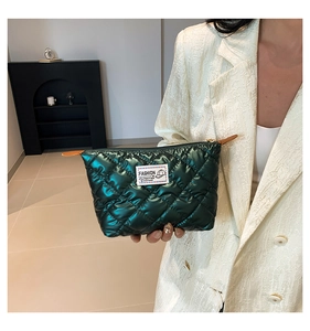 Dettaglio della mini borsa trapuntata verde scuro metallizzato con logo e tirante in pelle