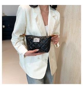 Pochette trapuntata in nylon nero con motivo a rombi tenuta in mano da una modella