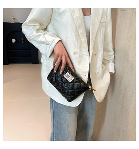 Gros plan d'une pochette noire matelassée avec fermeture dorée et étiquette de mode