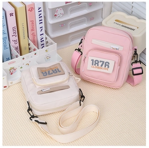 Detalle de bolsos bandolera de lona rosa y crema con correas ajustables y logotipos